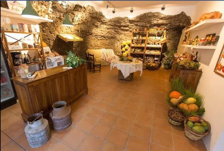 La tienda-cueva terminada, con la roca vista y los productos artesanos